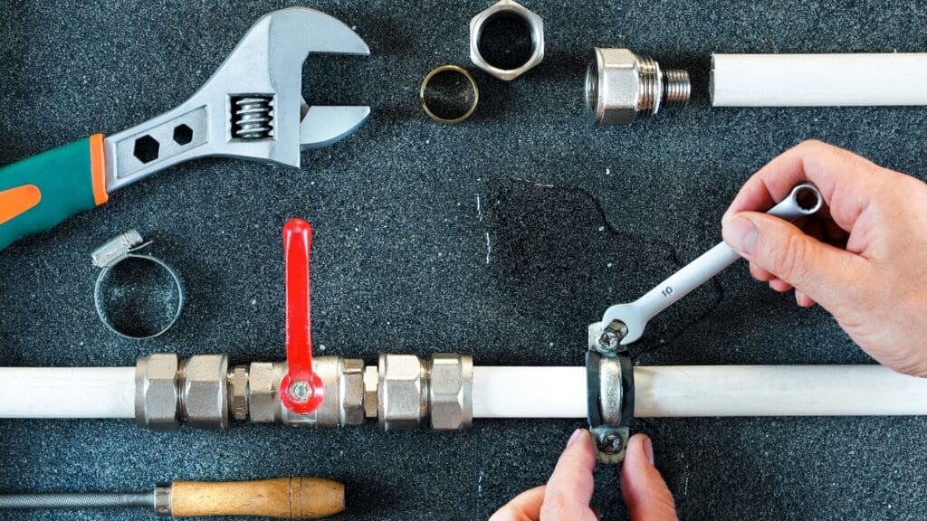 Plumber repairing a pipe valve with an adjustable wrench in Imperial Beach