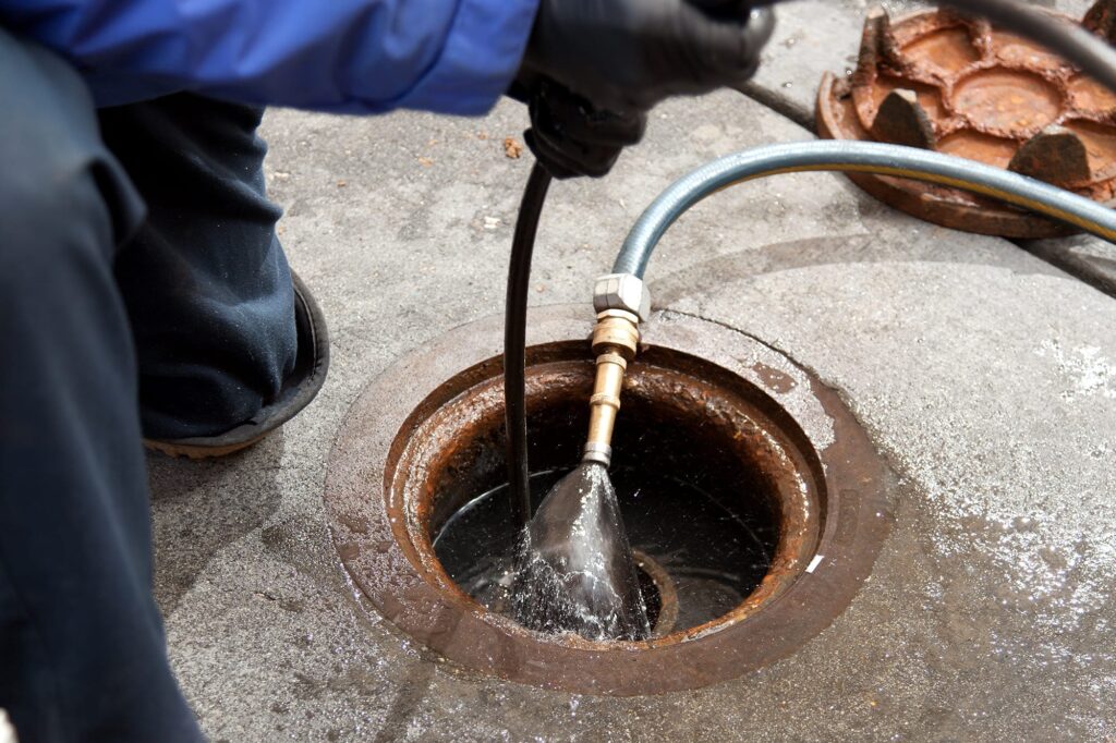 Plumber hydro jetting a sewer line through a manhole in Imperial Beach