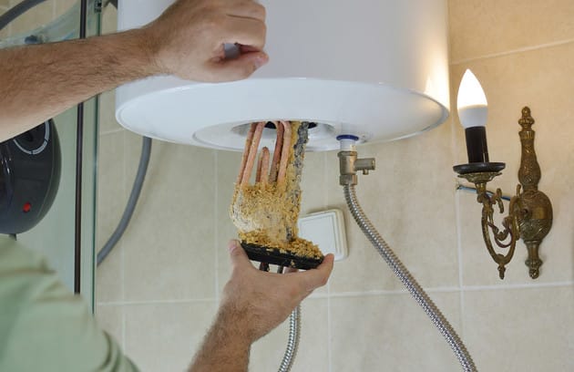 Technician removing mineral buildup from a water heater in Imperial Beach